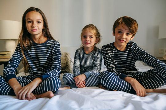 Portrait of kids wearing pajama resting on bed. 