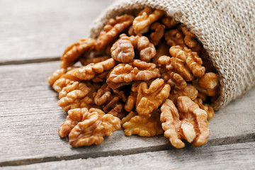 Obraz premium Walnuts in a burlap bag on a wooden gray background.