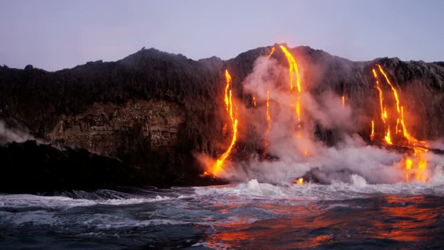 Red hot lava pouring into the Pacific ocean from erupting Kilauea volcano at night Hawaii seen before dawn USA 