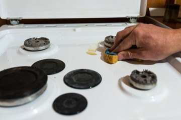 Caucasian man cleaning the dirty gas stove , focus on the cooffee spots.