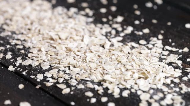 White Oat Flakes Lying on a Black Underground, Camera goes from Bottom to Top, High Angle