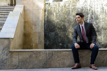 Portrait of young handsome businessman sitting outdoors