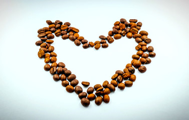The heart is made of coffee beans on a white background, the side edges are made of dark margins. Leave space for adding text.