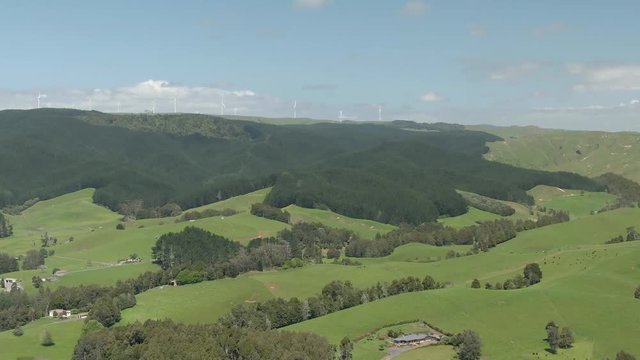 Areal footage above green hills and forests with a horizon full of windmills for collecting energy. 4k video quality