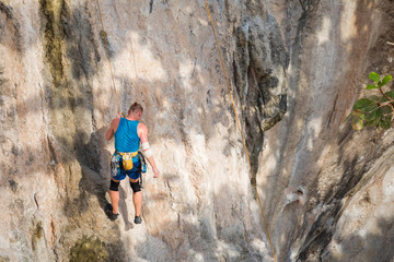 Fototapeta premium Young man rock climbing on karst limestone white mountain in Thailand