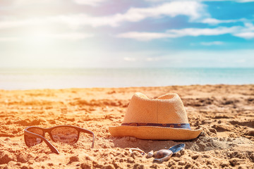 Fototapeta na wymiar Sunglass and cap on sand against turquoise sea.