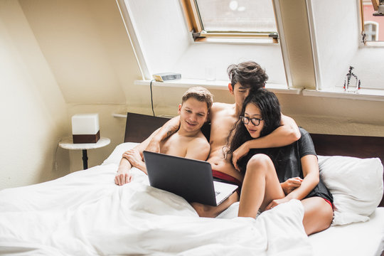 Party of three watching videos in bed