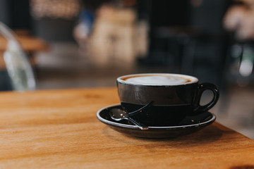 hot coffee in black cup on wooden table.