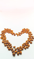 The heart is made of coffee beans on a white background, the side edges are made of dark margins. Leave space for adding text.