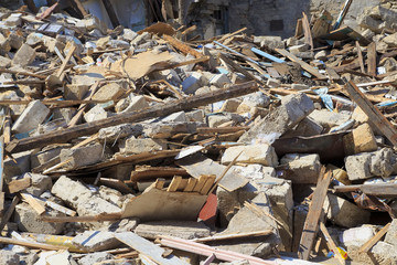 Disaster scene full of debris, dust and damaged house.