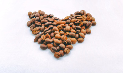 The heart is made of coffee beans on a white background, the side edges are made of dark margins. Leave space for adding text.