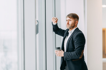 Coffee break after work in the office. Bright interior with a businessman.