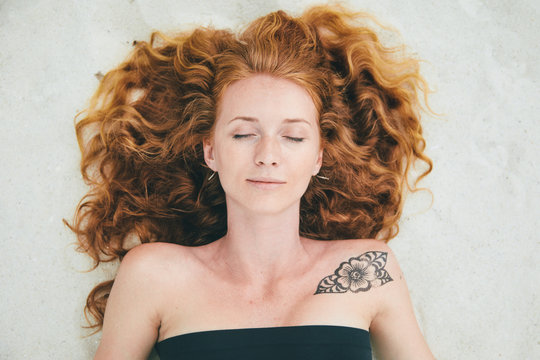 Ginger-haired woman lying on the beach