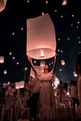 young woman release white lantern in the sky, Chiang Mai Thailand white lantern to release in the sky during Loi Krathong Yee Peng Festival © Fokke Baarssen