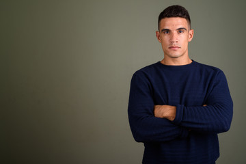 Young handsome man wearing sweater against colored background