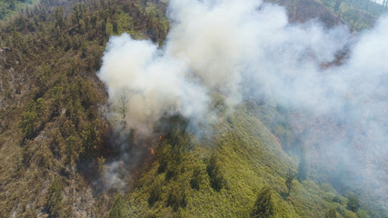 aerial view forest fire smoke on slopes hills. wild fire in tropical forest, Java Indonesia. natural disaster fire in Southeast Asia