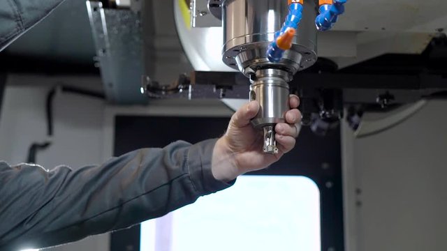 In the frame of the hand of the engineer and the mill for the CNC machine.