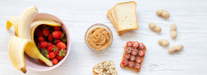 Vegan toasts with fruits, seeds, peanut butter. White wooden background, top view. From above. Flat lay.
