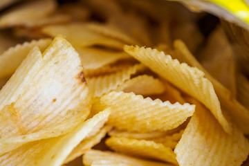 Potato chips in open snack bag close up