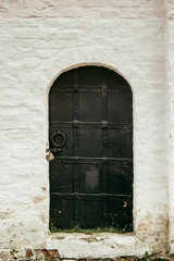 Black antique door in the old wall.