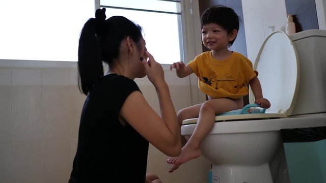 mother teach her son sitting on flush toilet