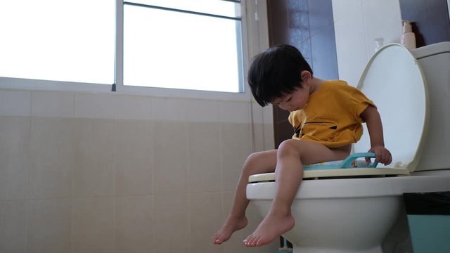 cute child sitting on flush toilet