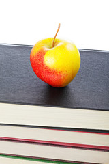 Red and yellow apple on book stack