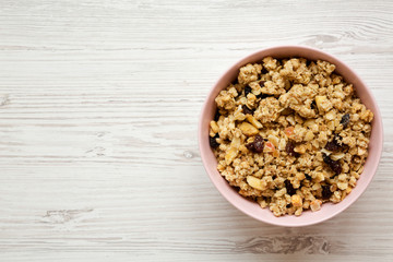 Fruit granola in pink bowl over white wooden surface, top view. Flat lay, from above, overhead.