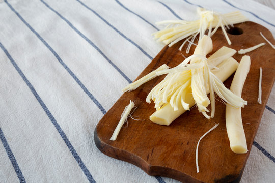 String cheese on rustic wooden board, side view. Healthy snack. Copy space.
