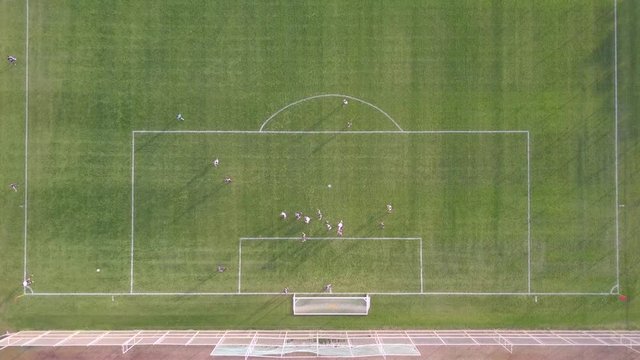 Corner kick - Top down aerial footage of a player kicking a corner kick at an amateur soccer match.