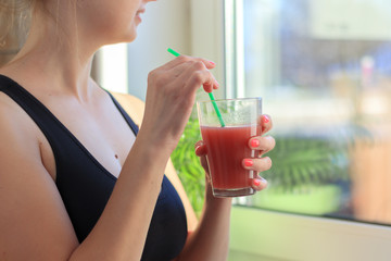 Sportswoman on detox diet purifying body by drinking healthy red cocktail after gymnastics