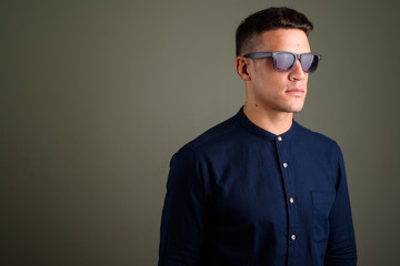 Fototapeta premium Young handsome businessman wearing sunglasses against colored ba