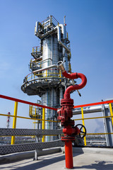Fireplug to extinguish the fire against the background of the oil column at the refinery