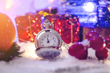 Pocket watch with a dial in the snow with gifts on the eve of holidays. Waiting for the magic of...
