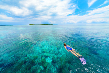 Woman snorkeling on coral reef tropical caribbean sea, turquoise blue water. Indonesia Wakatobi archipelago, marine national park, tourist diving travel destination