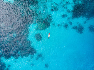 Aerial top down people snorkeling on coral reef tropical caribbean sea, turquoise blue water....