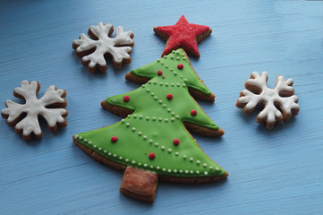 A set of gingerbread for Christmas. Christmas tree with a star surrounded by snowflakes, on a blue wooden background.