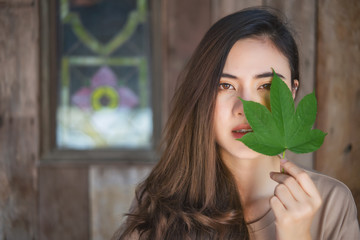 Fototapeta premium Attractive woman holds a green leaf close her half face. 
