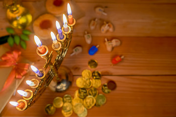 Jewish holiday hanukkah celebration with menorah (traditional candelabra), wooden dreidels (spinning top), donut, olive oil and chocolate coins on wooden table.