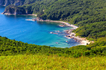 Fototapeta premium View of the beach with turquoise water and green hills in far east of Russia
