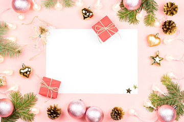 Christmas background with blank paper, presents, fir tree branches, golden decorations on pink. Copy space