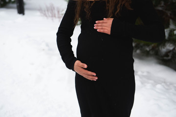 Detail of unrecognizable pregnant woman's belly in winter