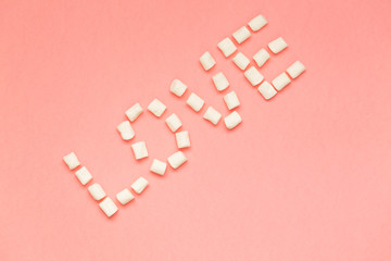 Marshmallows on pink background with copy space. Flat lay or top view. Background or texture of colorful mini marshmallows. Winter food background concept.