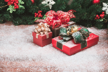 Stunning gift boxes have snowflake all over set on wood board, pine branches and Christmas ornaments background. Copy space at bottom left