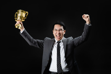 Asian man in formal suit happy with trophy.
