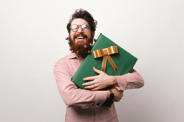 Smiling bearded man holding big gift box for christmas over white background