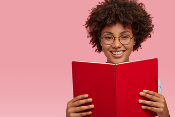 Merry pleased African American woman with pleased expression, wears optical glasses for good...