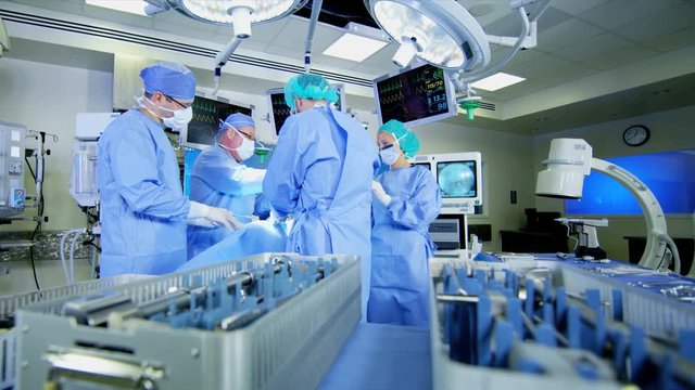 Medical healthcare hospital male and female surgeons performing Orthopedic operation in theatre using monitors and modern technology 