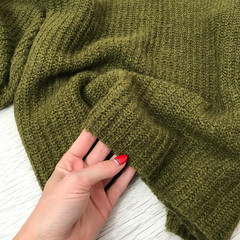 Green wool sweater close up on wooden background