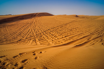 Fototapeta na wymiar Tire tracks through the desert sand dunes. Feeling lost and alone in this world.